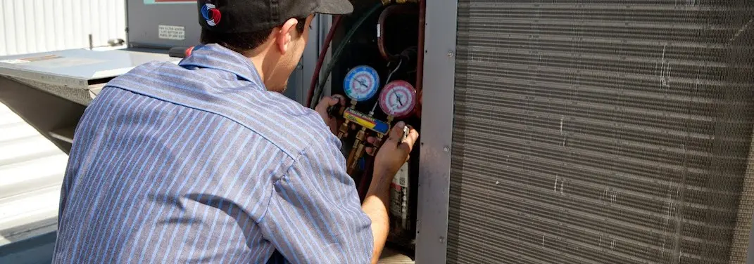 HVAC technician servicing a condenser unit in Sans Souci